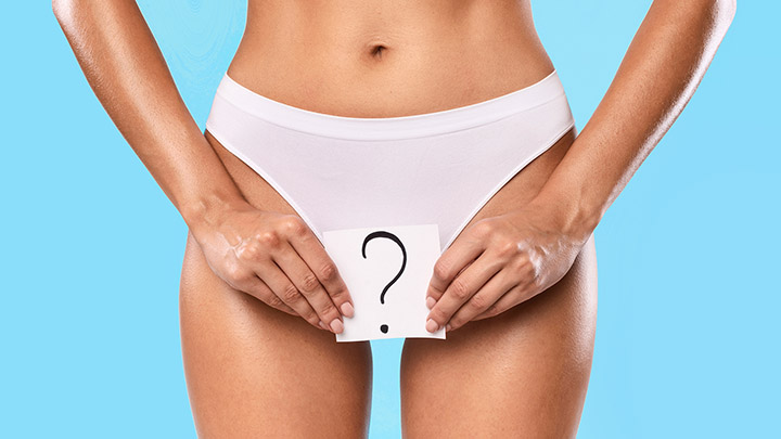 Imagem mostra uma mulher da cintura para baixo, segurando um papel com uma interrogação que demonstra dúvidas em relação a assuntos ginecológicos